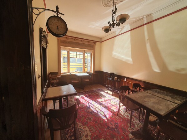 A room with a large window, a clock, and a chandelier. - Le Salon des Inconnus (Namur)