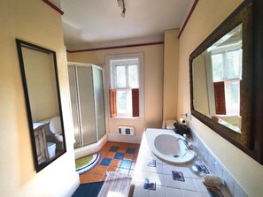 A bathroom with a shower, toilet, sink, and large mirror.