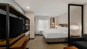 Una habitación de hotel con cama, televisión, escritorio y zona de estar.