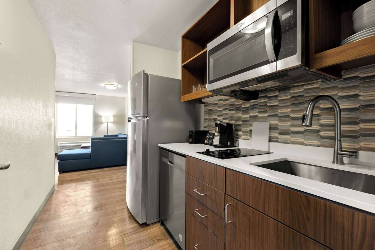 A modern kitchen with wooden cabinets, a stainless steel sink, and a built-in microwave.