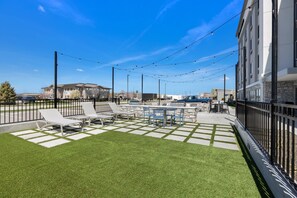 An outdoor patio area with lounge chairs, a barbecue grill, and string lights.