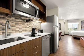 Una cocina moderna con microondas integrado, refrigerador de acero inoxidable y lavavajillas.