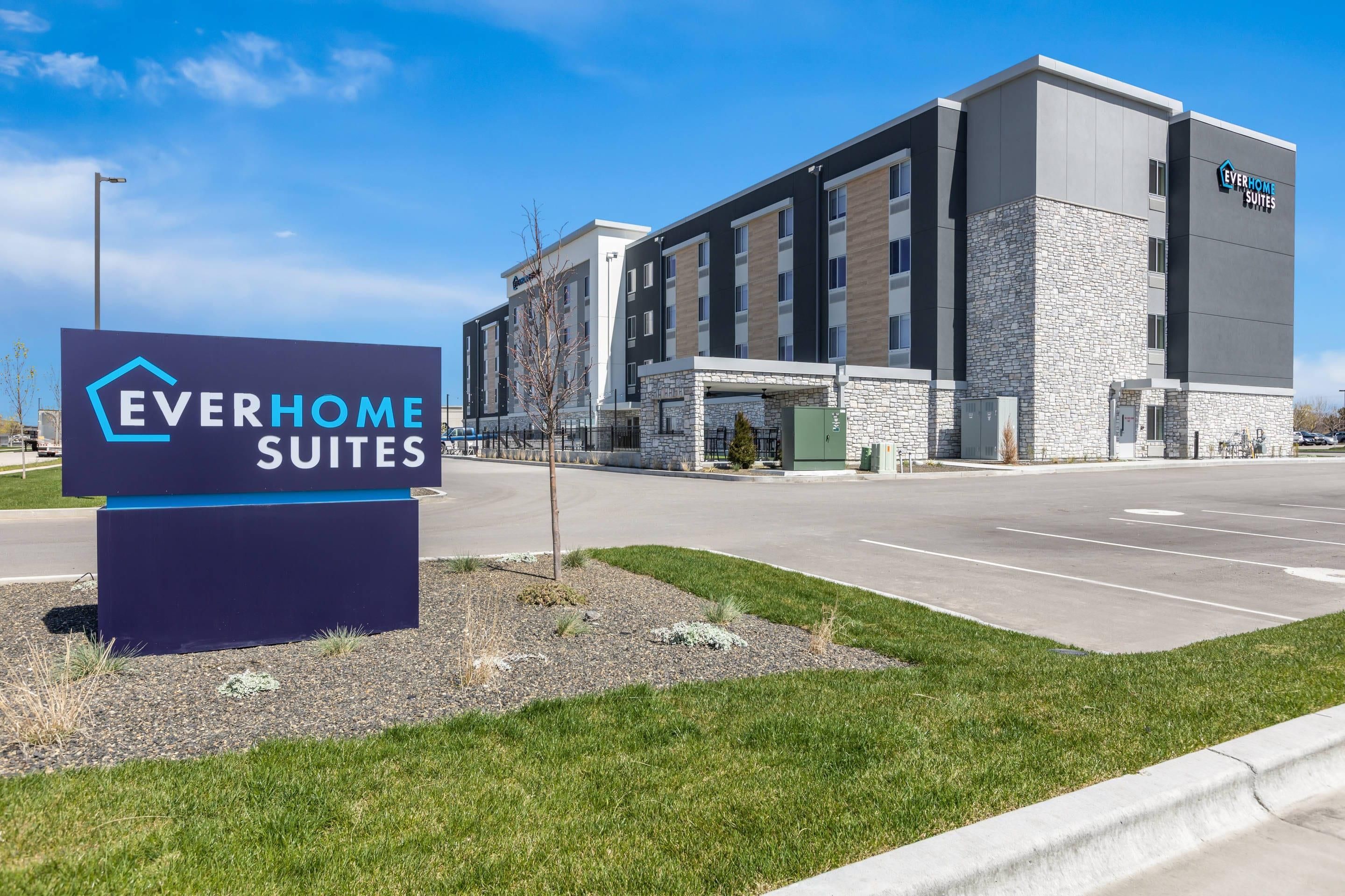A modern hotel building with a sign for Everhome Suites.