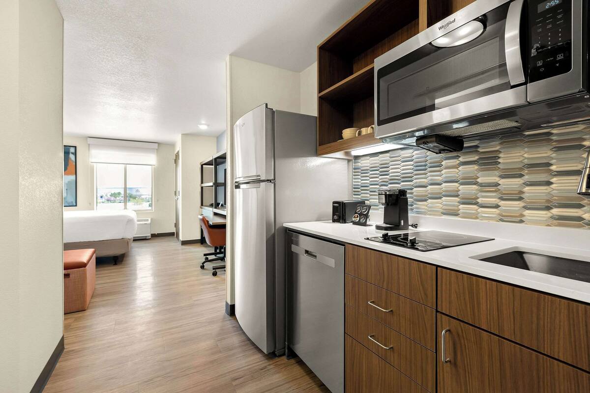A modern kitchen with stainless steel appliances, a dishwasher, and wooden cabinets.