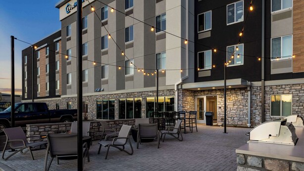 A hotel with outdoor seating, stone facade, and string lights. - Everhome Suites Nampa Boise (Nampa)