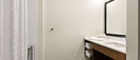 A modern bathroom with a white sink, a mirror, and a shower curtain.