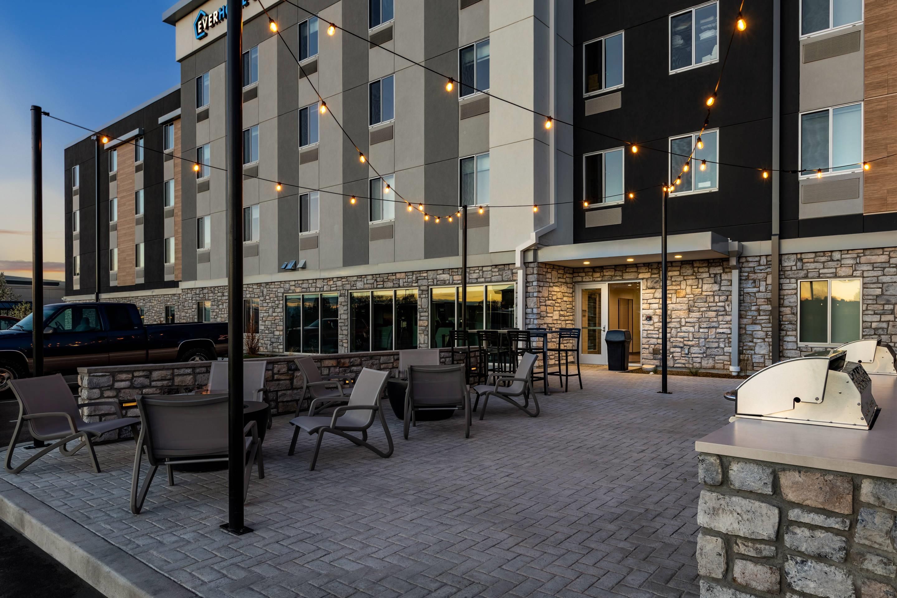 A hotel with outdoor seating, stone facade, and string lights.
