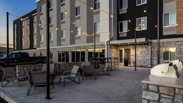 A hotel with outdoor seating, stone facade, and string lights.