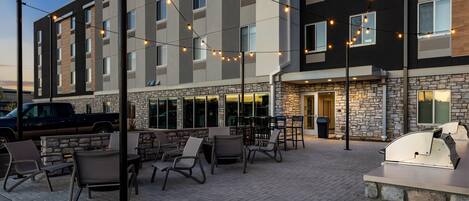 A hotel with outdoor seating, stone facade, and string lights.