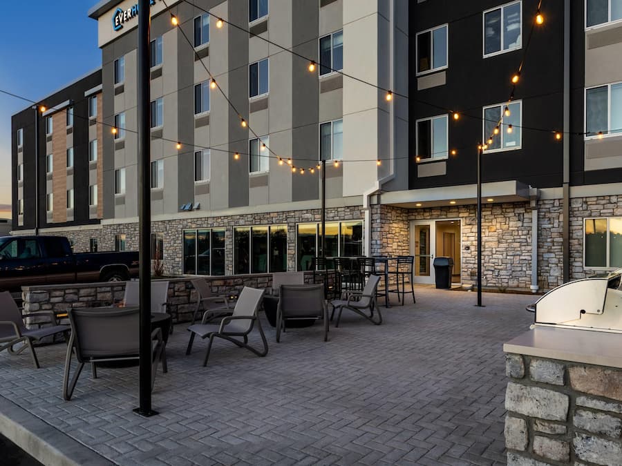 A hotel with outdoor seating, stone facade, and string lights.