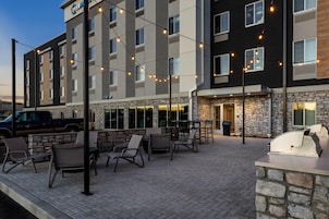 Un hotel con terraza, fachada de piedra y luces colgantes.