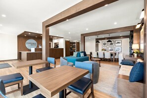 A modern hotel lobby with a reception desk, seating area, and a staircase leading to the upper floors. - Everhome Suites Nampa Boise (Nampa)