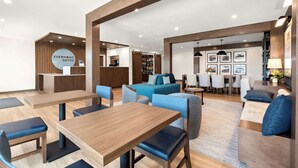 A modern hotel lobby with a reception desk, seating area, and a dining space. - Everhome Suites Nampa Boise (Nampa)
