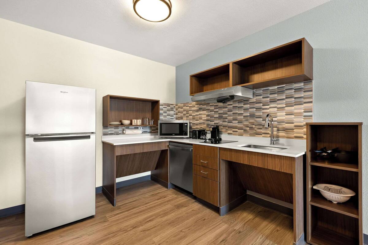 A modern kitchen with a refrigerator, microwave, and dishwasher.