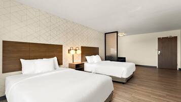 Una habitación de hotel con dos camas, un cabecero de madera, un papel tapiz con diseño geométrico y una puerta.