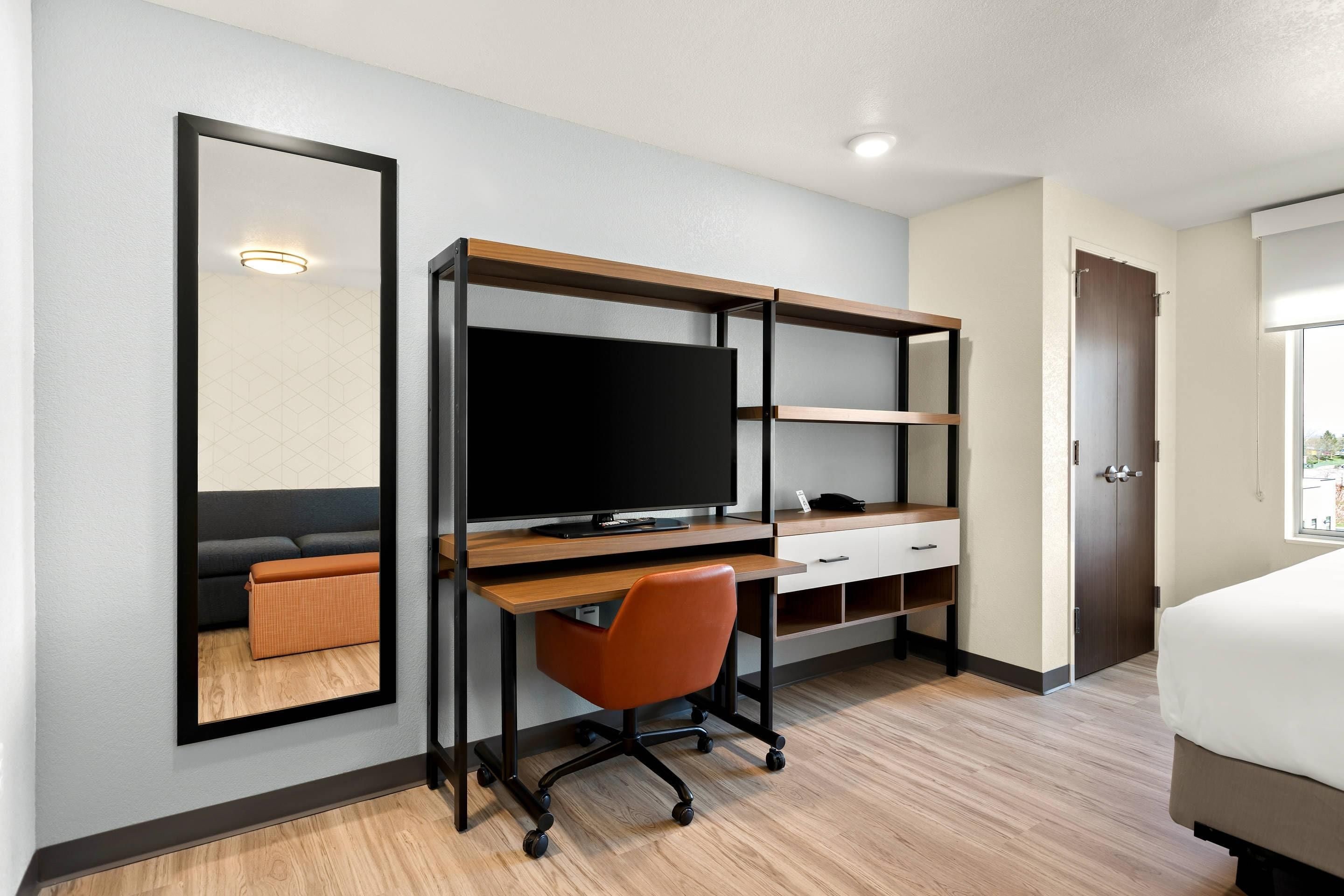 Une chambre d’hôtel équipée d’un bureau, d’une chaise, d’une télévision et d’un lit.