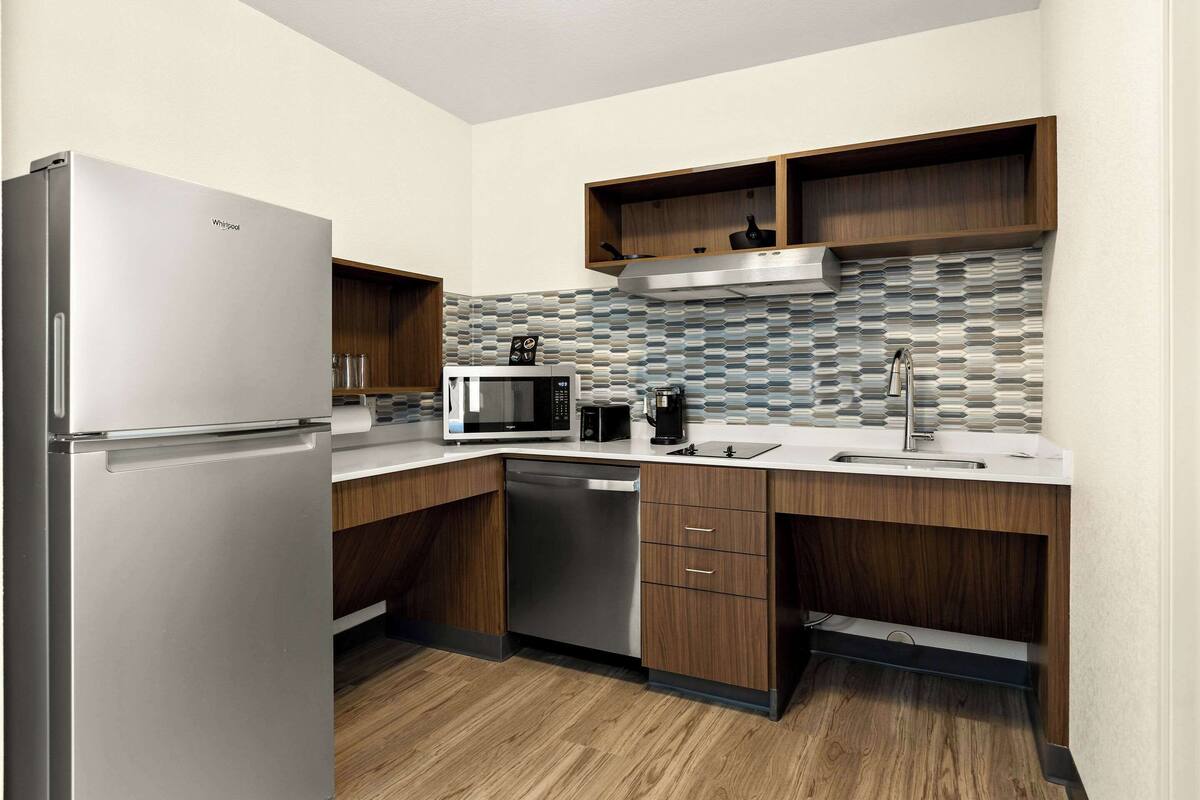 A compact kitchen with a refrigerator, microwave, coffee maker, and dishwasher.
