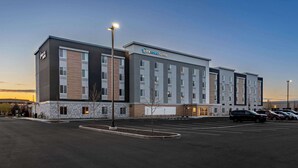 A modern hotel with a stone facade, multiple floors, and a parking lot. - Everhome Suites Nampa Boise (Nampa)
