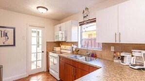 Une cuisine avec des meubles blancs, un plan de travail en granit, une cuisinière et une fenêtre donnant sur un beau paysage.