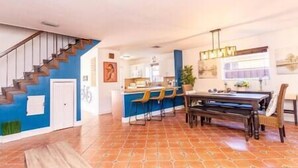 Une cuisine spacieuse avec un coin repas, un escalier et un mur d’accent bleu.