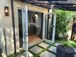 Un área de estar al aire libre de estilo moderno con un banco acolchado, una mesita y una planta en maceta.