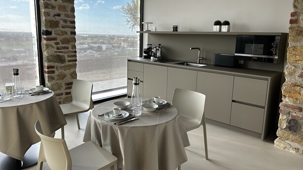 A modern kitchen with a large window, a dining area with a table set for two, and a collection of decorative plates on the wall.