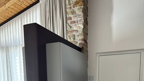 A modern room with a built-in wardrobe, a stone accent wall, and a wooden floor.