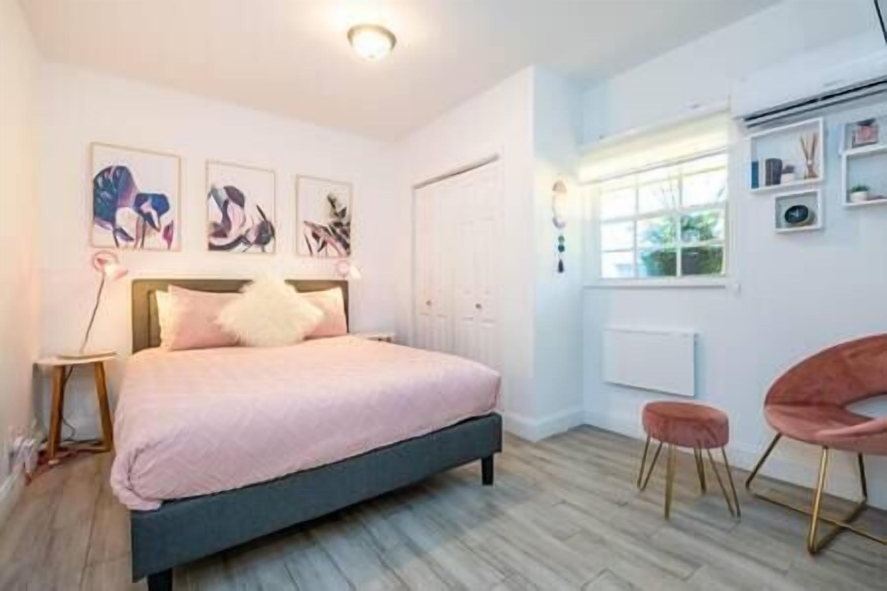A bedroom with a bed, a bedside table, a chair, and a window.