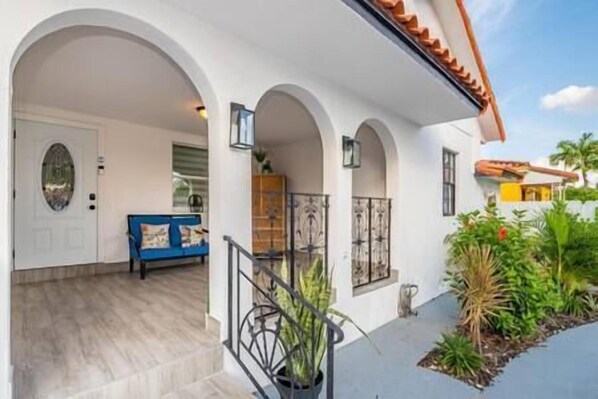 A house with a covered porch, a blue sofa, and potted plants.