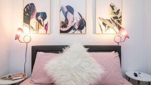 Un dormitorio con una cama, una mesita de noche y tres cuadros enmarcados en la pared.