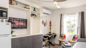 Un espacio habitable compacto con kitchenette, comedor y zona de estar con vistas al exterior.