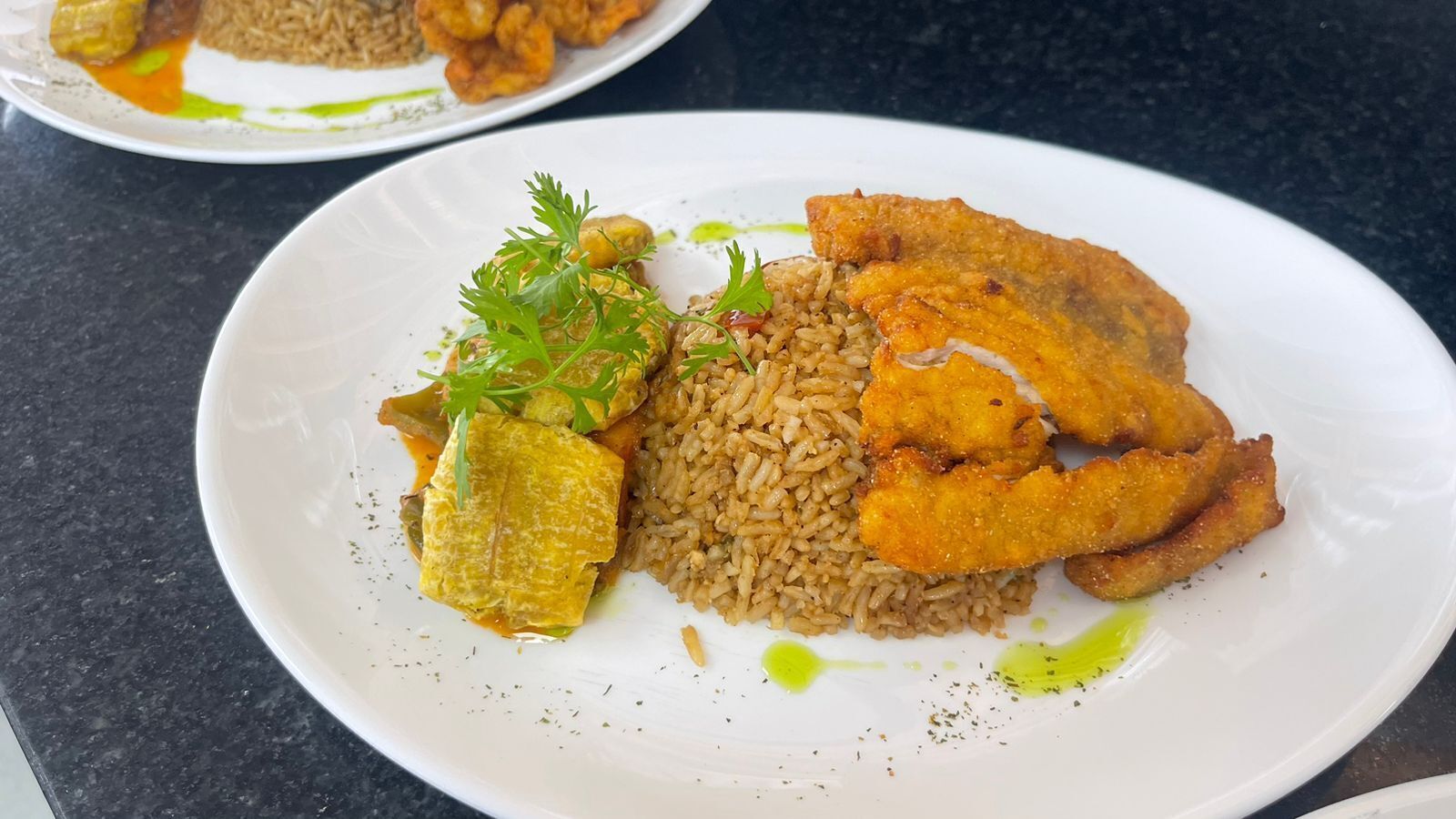 A plate with fried fish, rice, and a side of pickles.