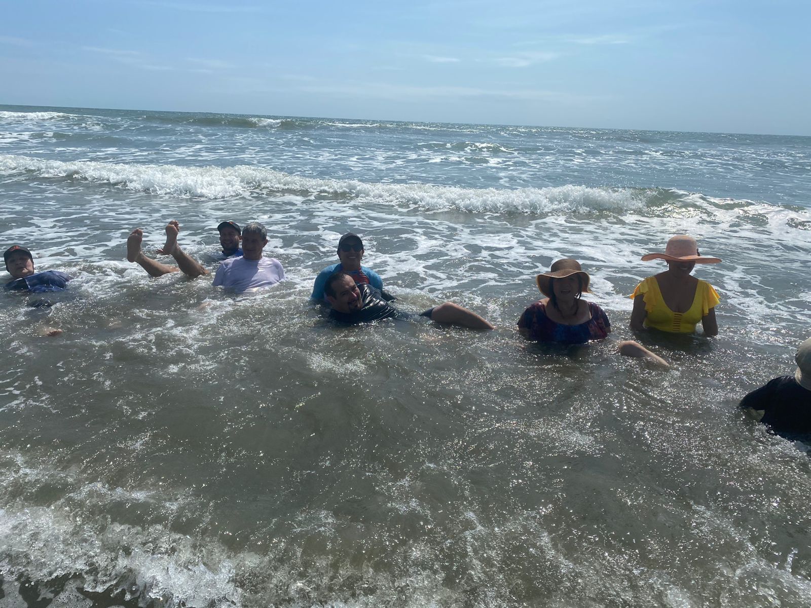 A group of people in a shallow sea with waves.