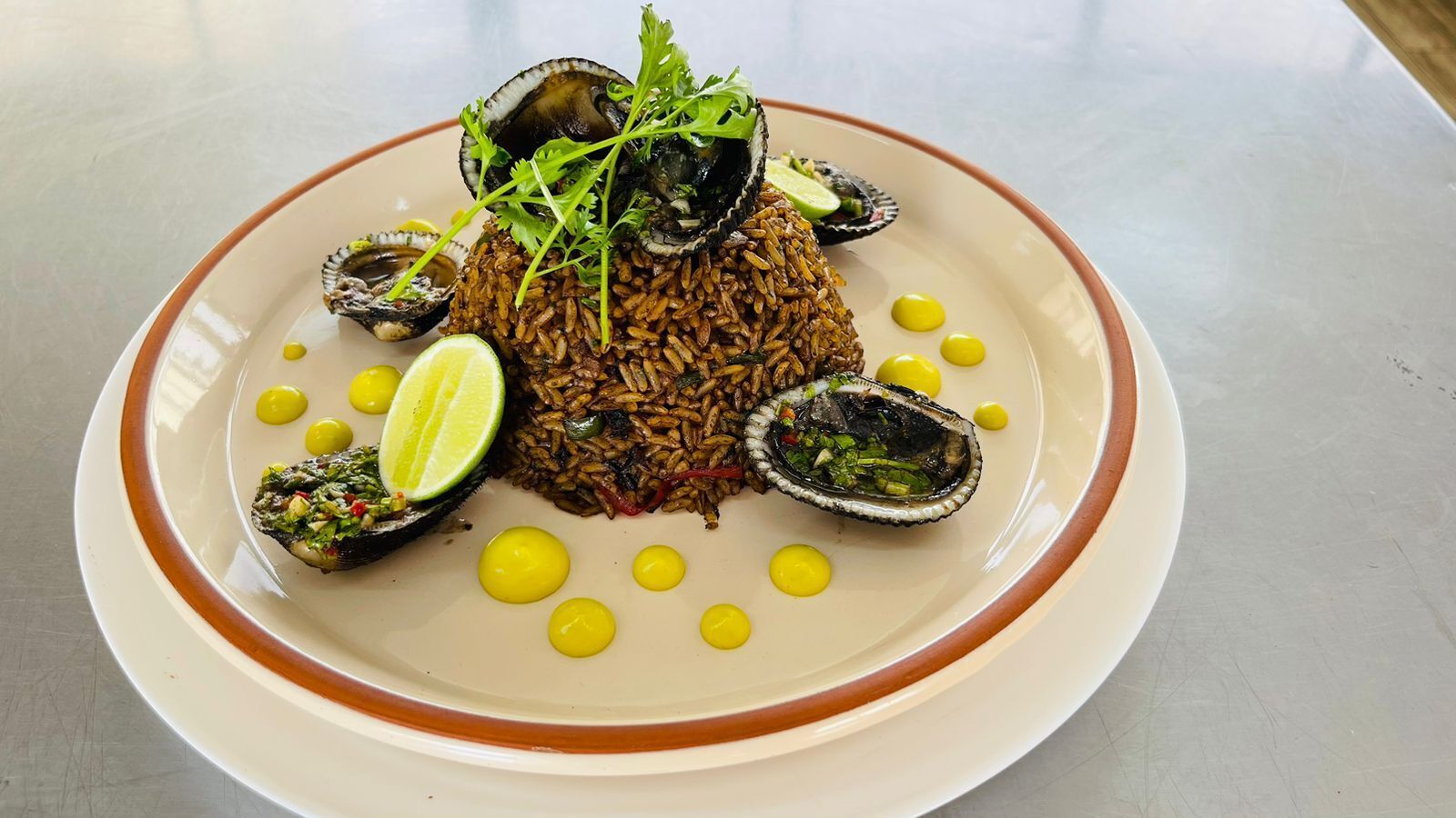 A plate of food with rice, mussels, and lime.