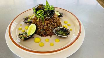 Un plato de comida con arroz, mejillones y lima.