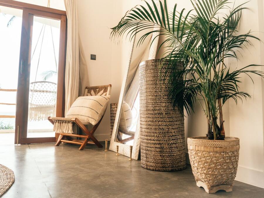 Una habitación con una cesta grande de mimbre, una mecedora de madera y una planta en maceta.