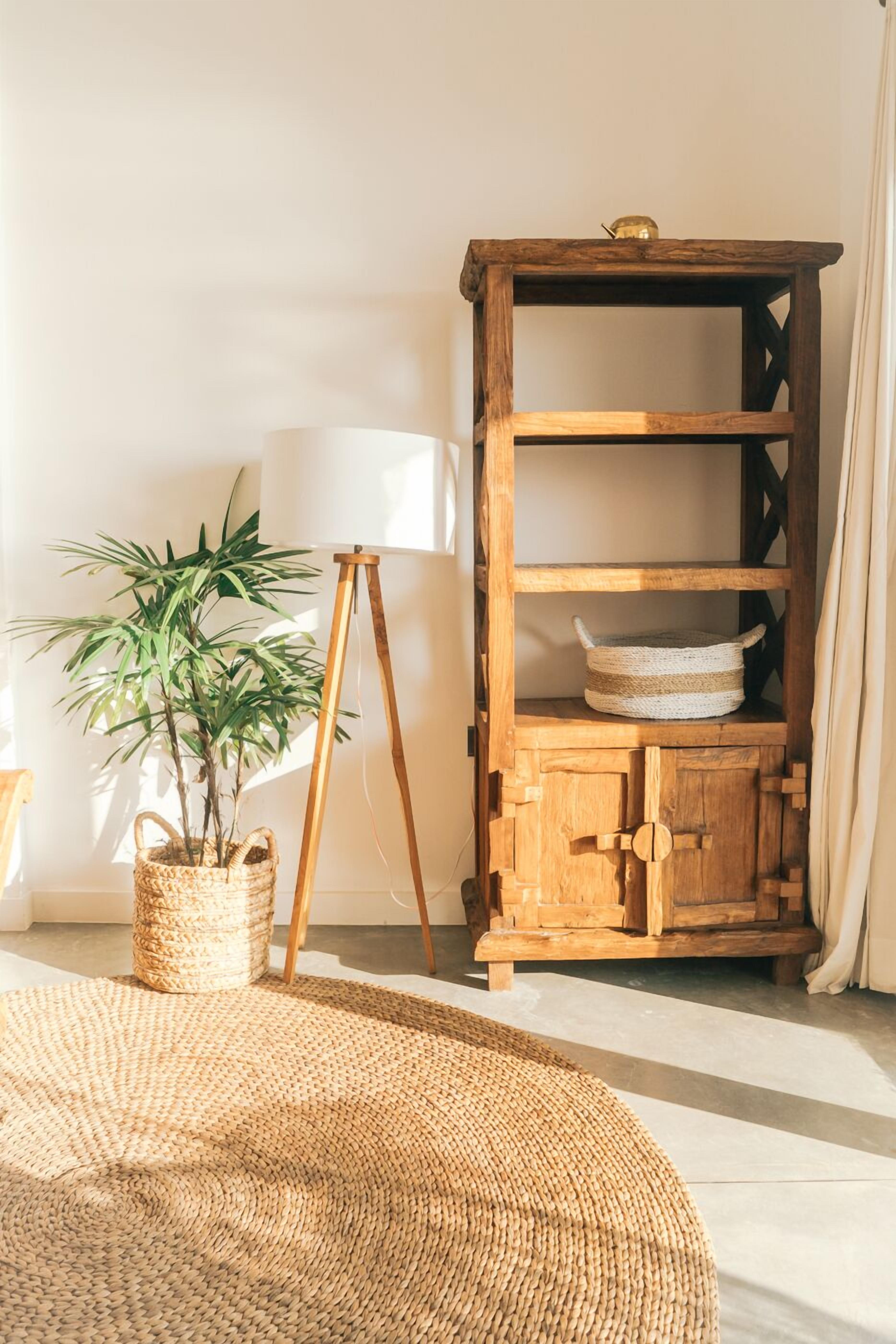 Ein Zimmer mit einem Holzkasten, einer Stehlampe und einem gewebten Teppich.