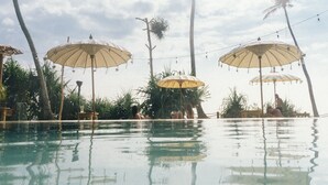 Un espace piscine agrémenté de parasols et de palmiers.