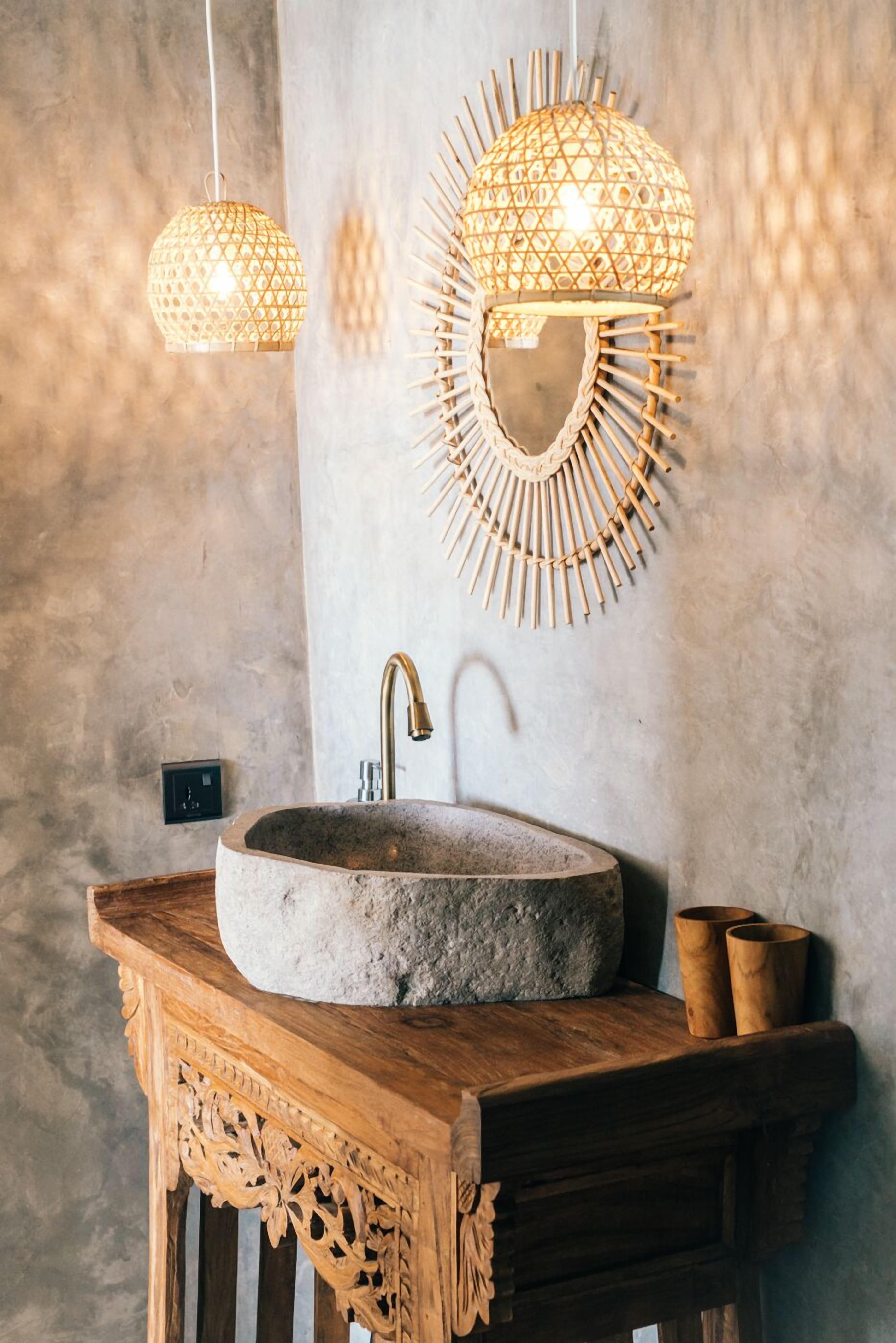 A bathroom with a stone sink, wooden vanity, and two hanging lights with a geometric design.