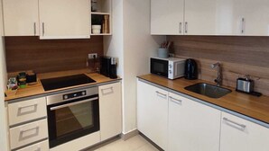 Une cuisine moderne avec des meubles blancs, un four encastré, un four à micro-ondes et un évier.