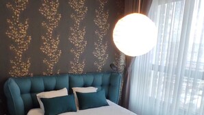 Une chambre à coucher avec un grand lit, une tête de lit, une table de chevet et une fenêtre avec des rideaux.