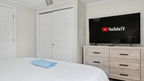 Una habitación de hotel con una cama, un televisor montado en la pared y un aparador de madera.