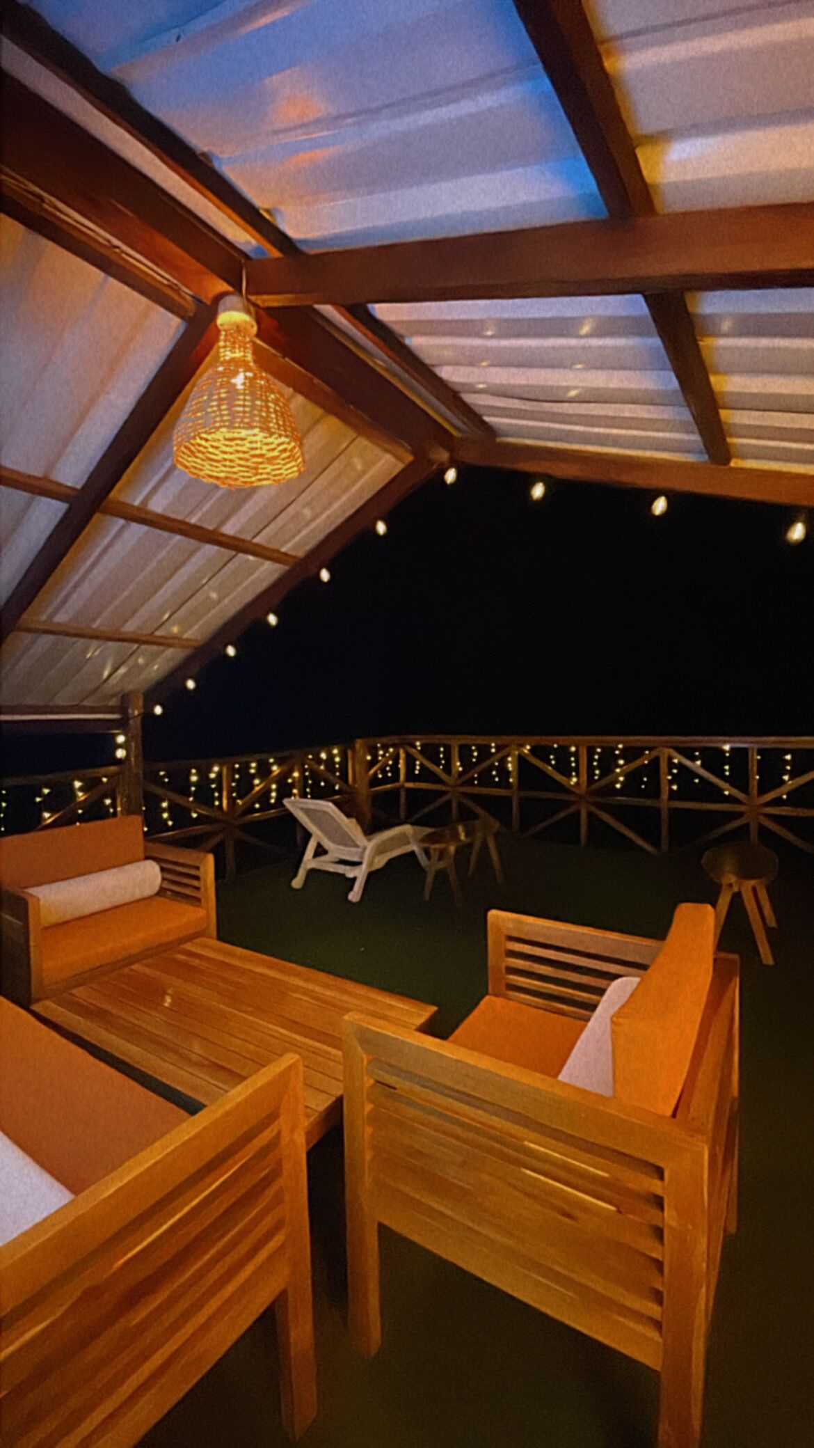 Ein überdachter Außenbereich mit Holzmöbeln und Lichterketten.