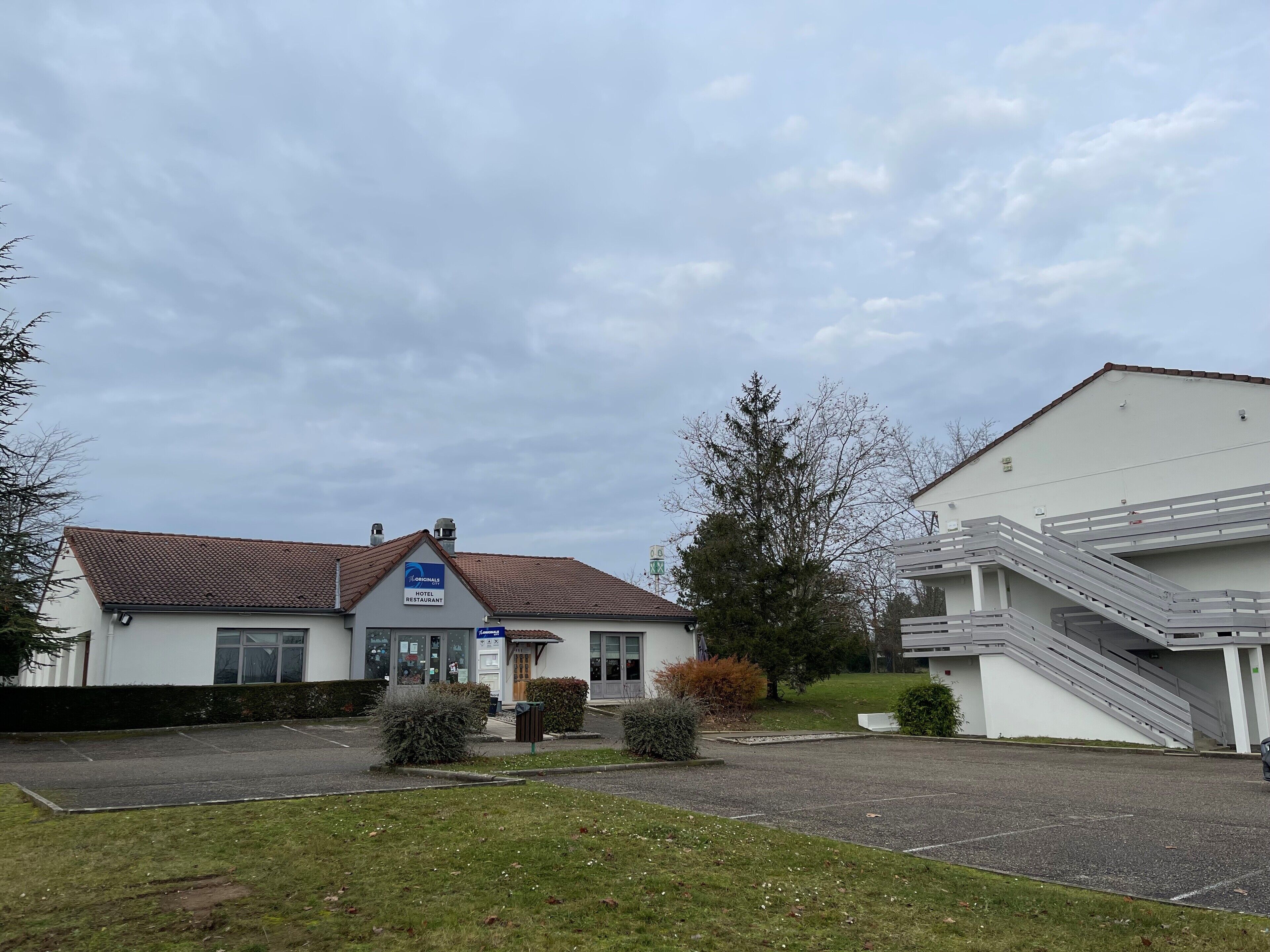 A hotel with a tiled roof, a sign for the original restaurant, and a staircase leading to an upper level.