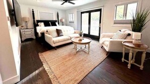 A spacious bedroom with a large bed, a ceiling fan, a sitting area with a coffee table, and a view through a sliding glass door. - Chef's Kitchen + Minutes to Boyne Mountain + Walk Downtown (Boyne City)