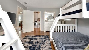 A modern bedroom with a bunk bed, a dresser, a washing machine, and a mirror with lights. - 4BR Home w/ Private Dock and Fenced Backyard and Firepit. Minutes from the Beach (St. Augustine)