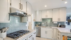 A modern kitchen with white cabinets, a stainless steel range hood, a dishwasher, and a marble countertop. - Monterey Bay 4BR, 3BA, Hot Tub Near Beaches & Golf (Seaside)