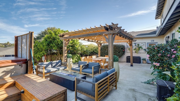 A patio area with wooden furniture, a pergola, and potted plants. - Monterey Bay 4BR, 3BA, Hot Tub Near Beaches & Golf (Seaside)