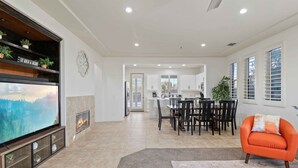 A spacious living area with a fireplace, a television, and a dining area with chairs and a table. - Secluded Getaway w/ Self Check-in & Slt Water Pool (Indio)
