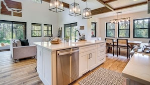 A spacious kitchen with a large island, wooden beams, and pendant lighting.